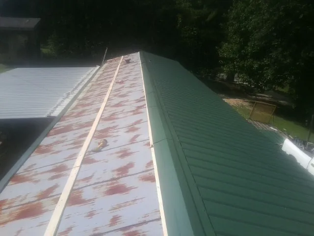 Old rusted panels beside newly installed green metal roofing — Wind Damage Roof Repair by Roofing Brothers in New Britain