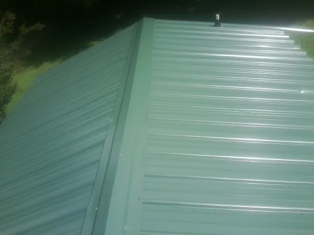 New green metal panels meeting at the ridge of a roof — Flat Roof Repair work by our crew in New Britain