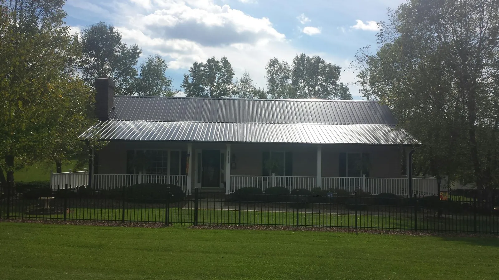 Gray metal roof on a brick ranch with a full width front porch — Gutter Guard Installation work by our crew in New Britain