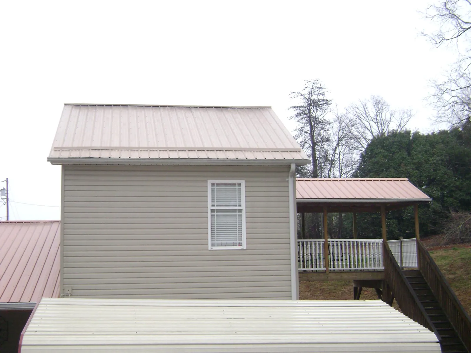 Tan metal roofs on a two story addition and attached porch, from a Roof Replacement job in New Britain