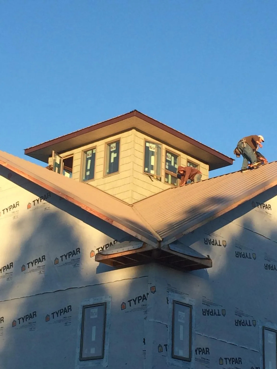 Roofers working around a rooftop cupola on a new metal roof at sunset — Roof Waterproofing in New Britain by Roofing Brothers